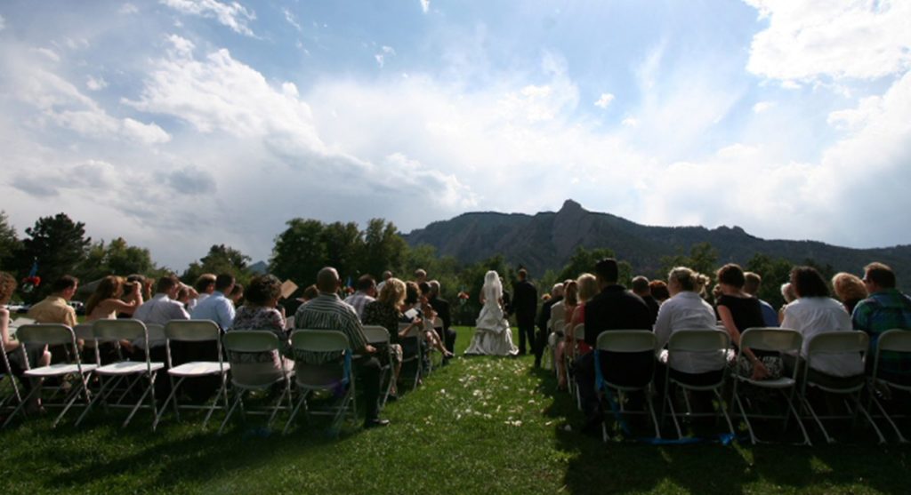 Wedding scene in meadow with many people and bride and groom in center