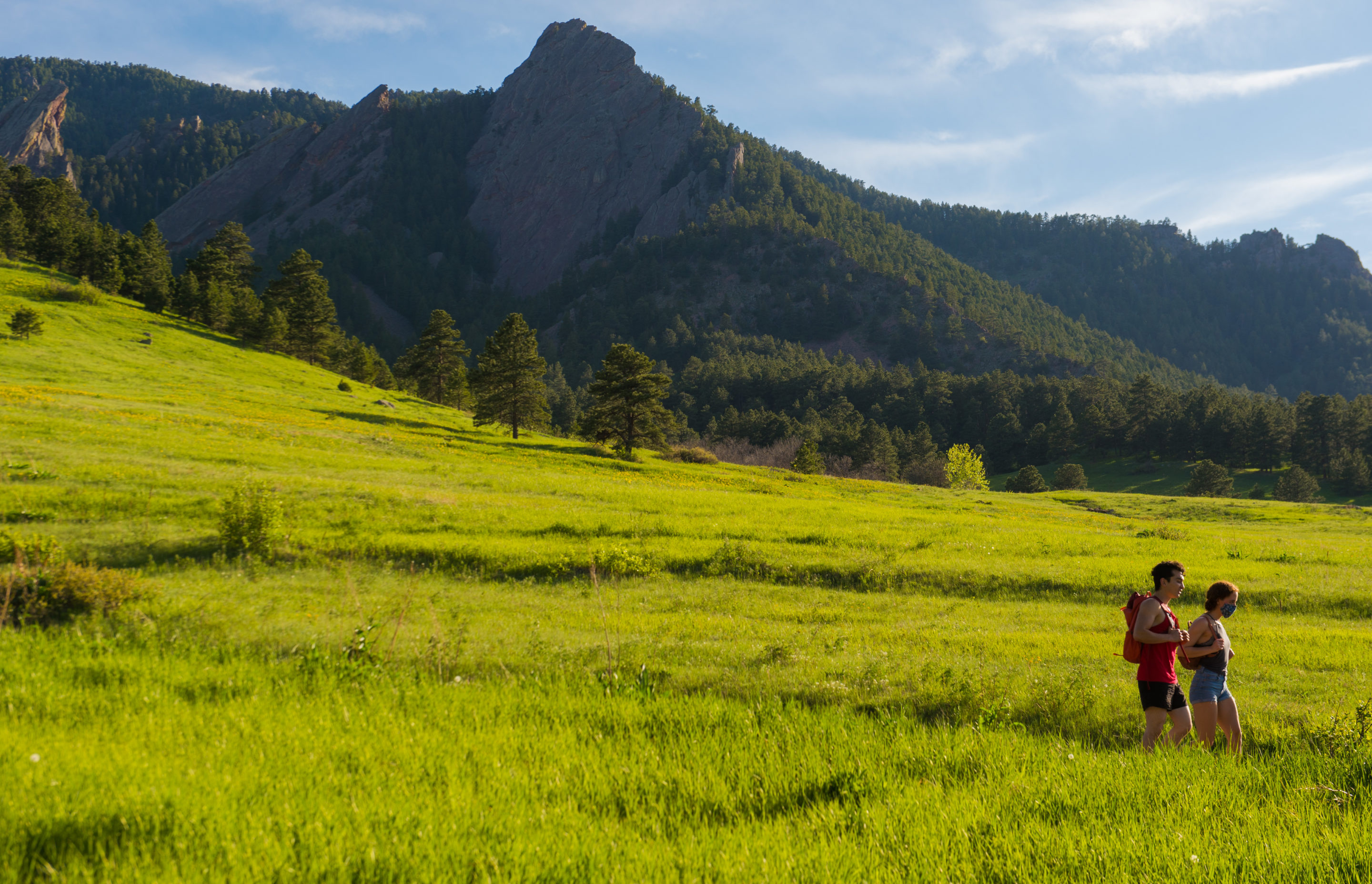 Couple hiking in Chautauqua Meadow with Flatirons behind