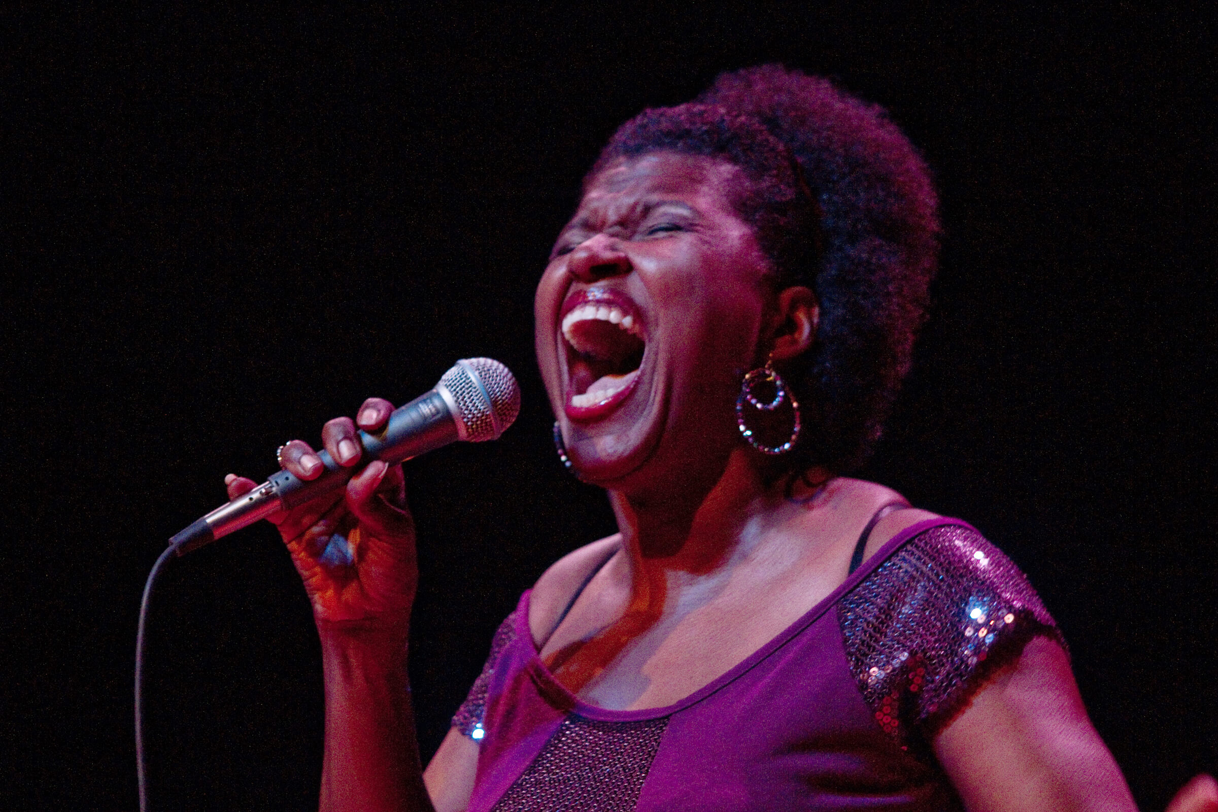 woman holds microphone and sings with eyes closed