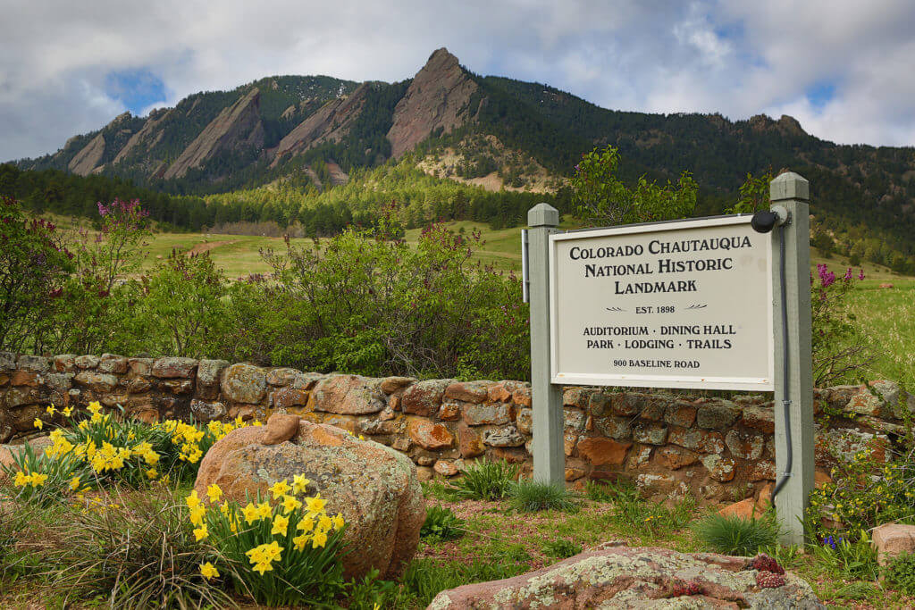 Chautauqua entrance in spring with National Historic Landmark sign and Flatirons behind
