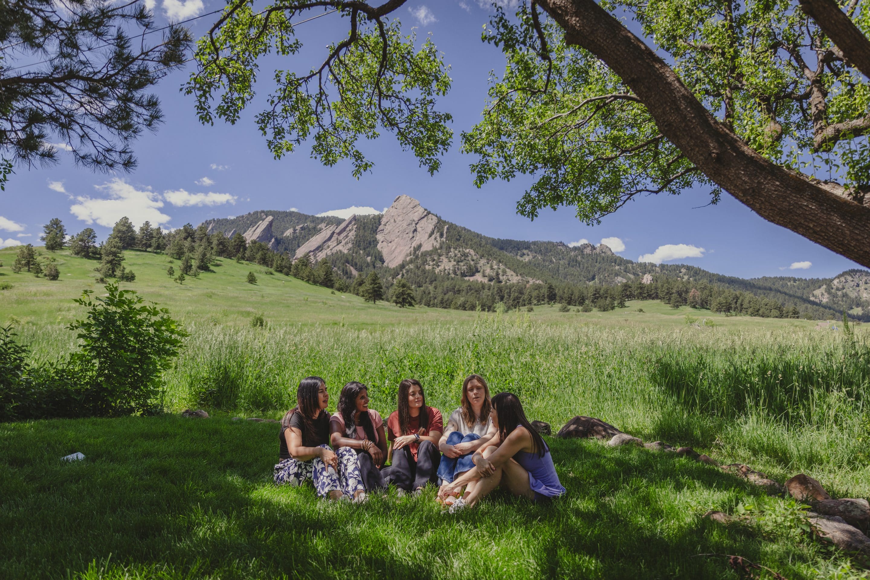Woman with glass of wine sitting in chair and looking at Flatirons mountains